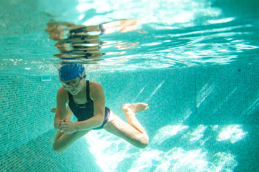 girl swimming under water in pool.