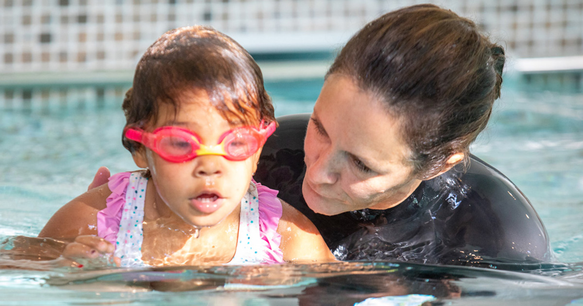 Swimming instructor teaching child in pool.